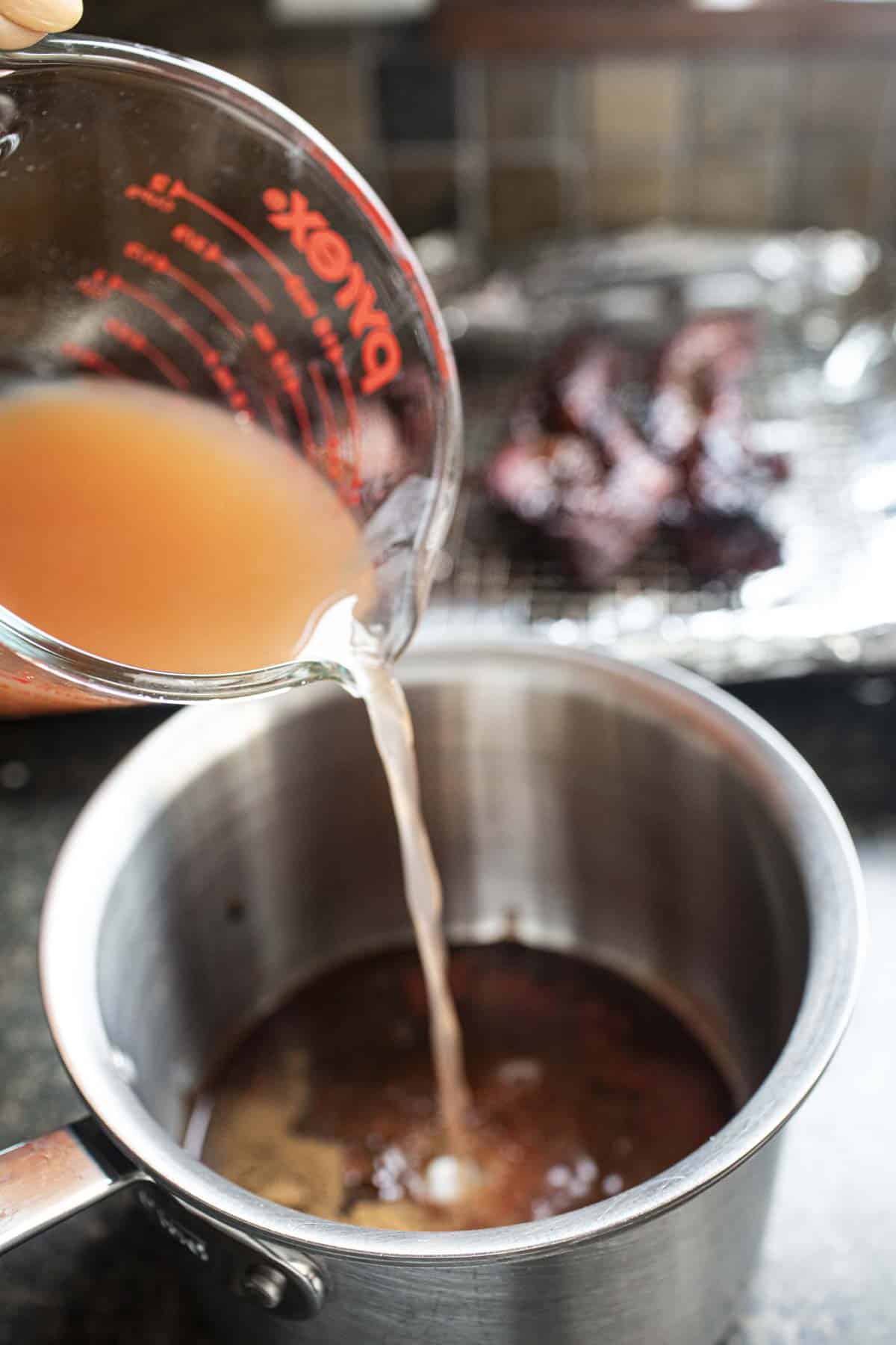 stock pouring into Moo Dang sauce in a pan. 