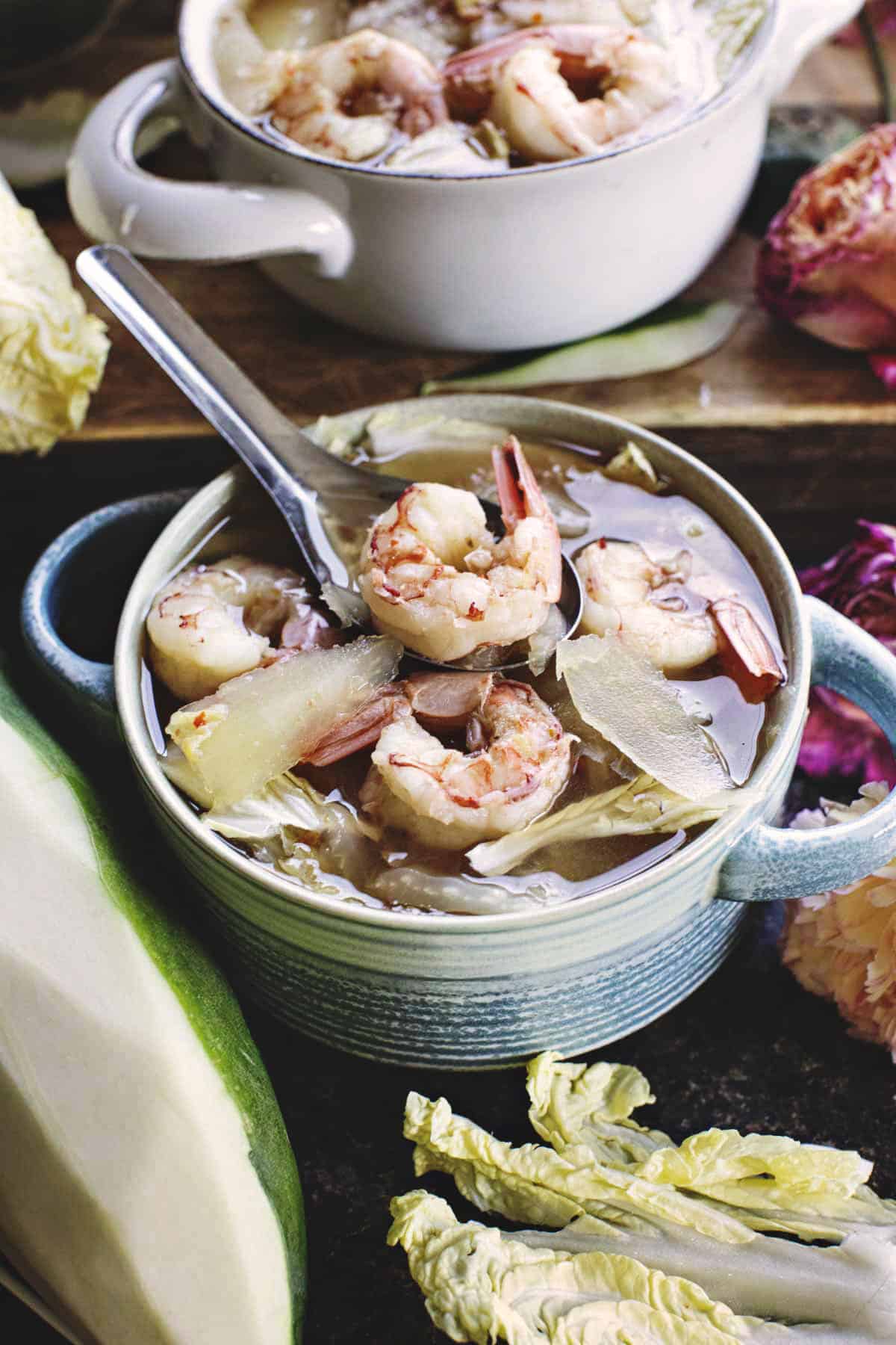 Thai papaya curry in a bowl with spoon lifting a shrimp. 