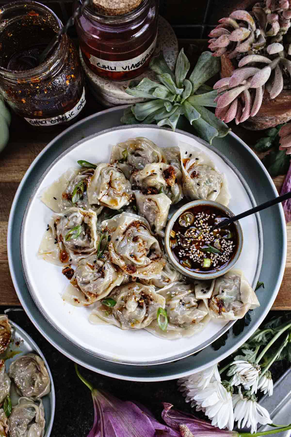 Shrimp and pork wontons on a plate with black dipping sauce. 