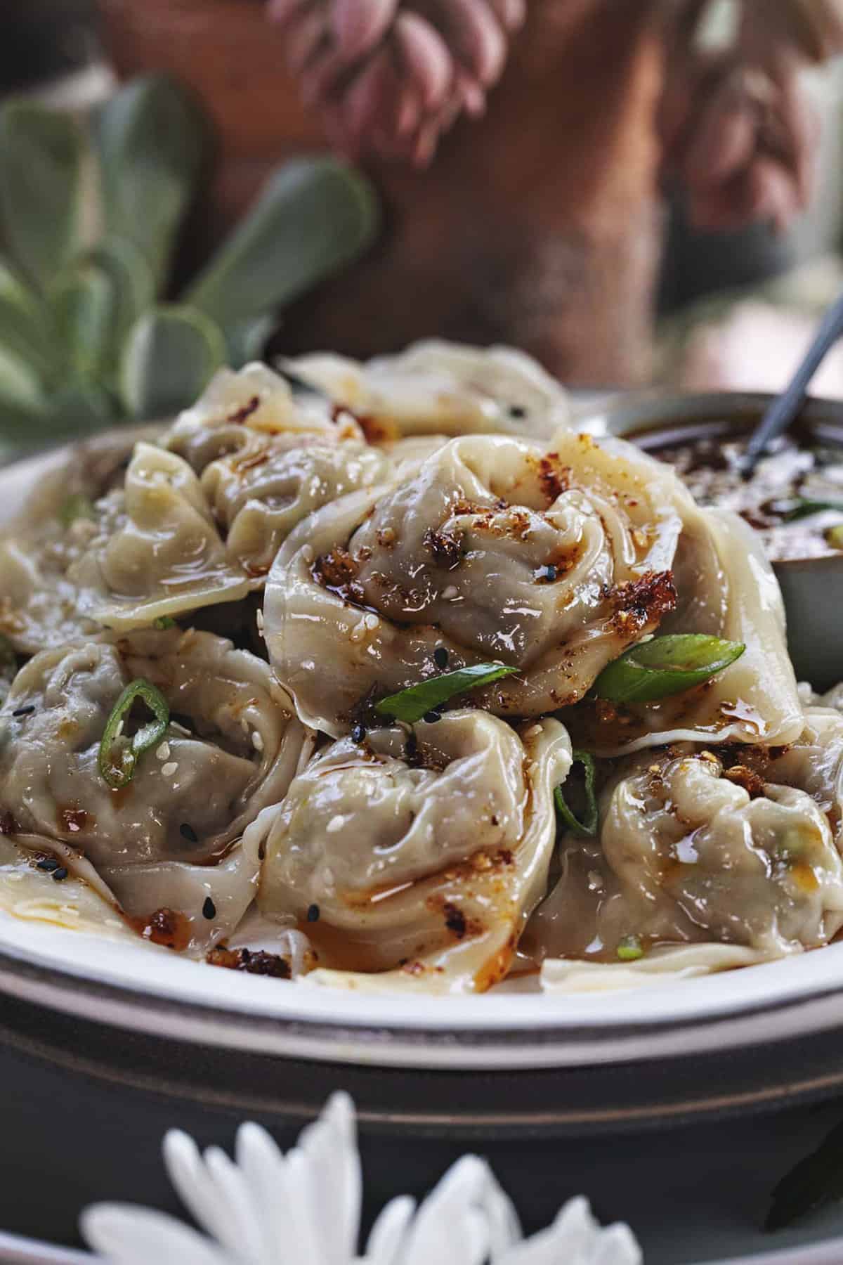 close up of wontons with garlic oil on a plate.