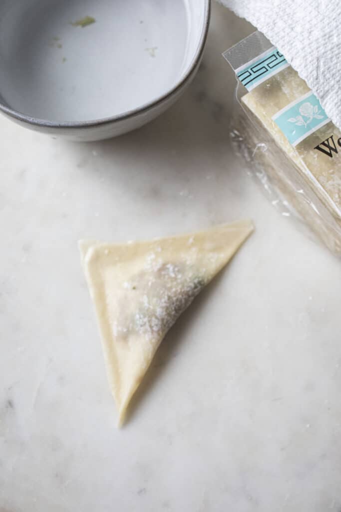 a triangle wonton wonton on a cutting board. 