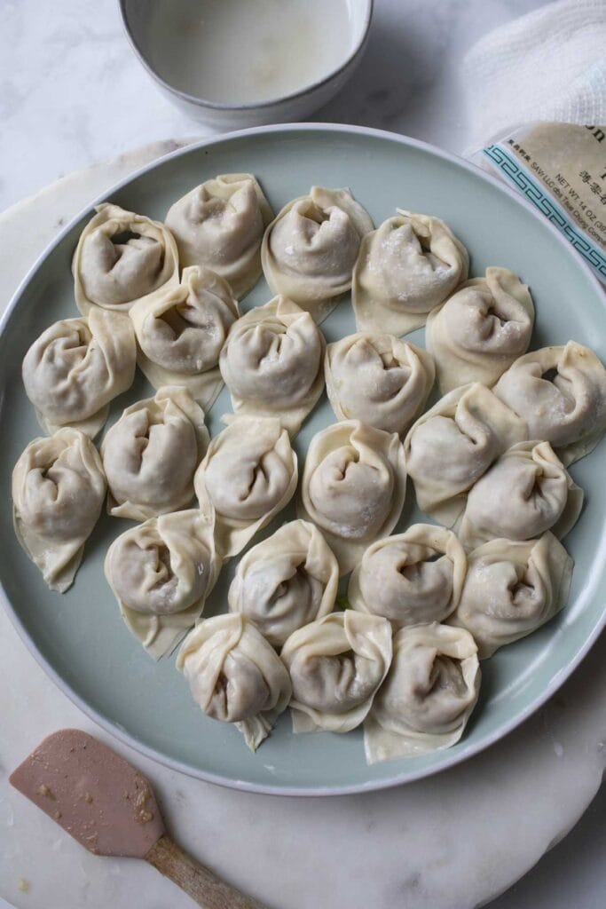 A plate full of boat shaped wontons.