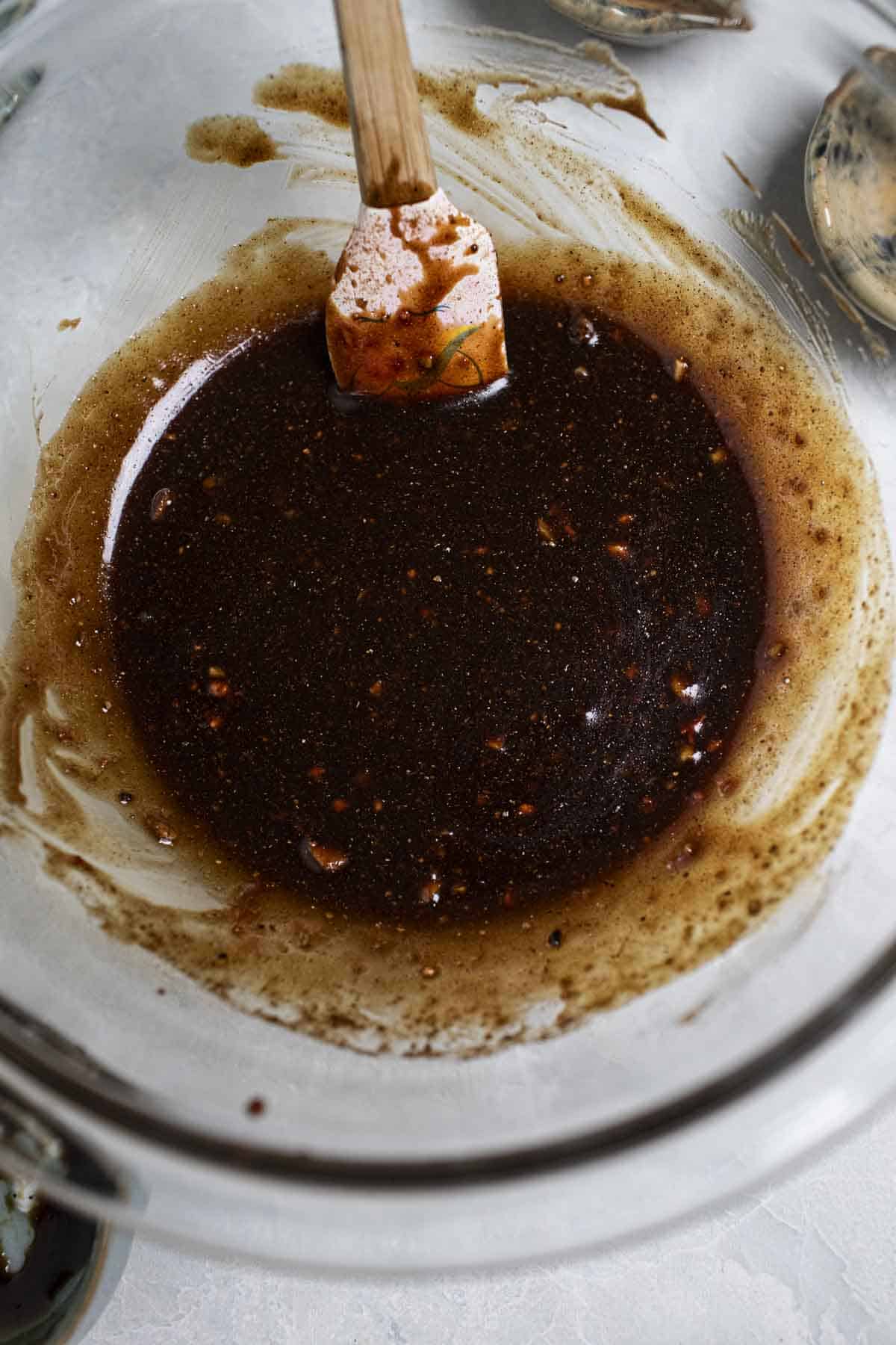 Red khao moo dang sauce in a bowl with spatula. 