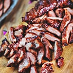 Red pork slices on a cutting board.