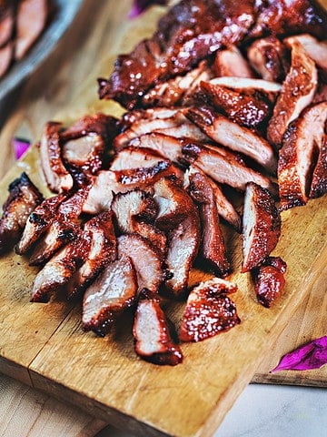 Red pork slices on a cutting board.