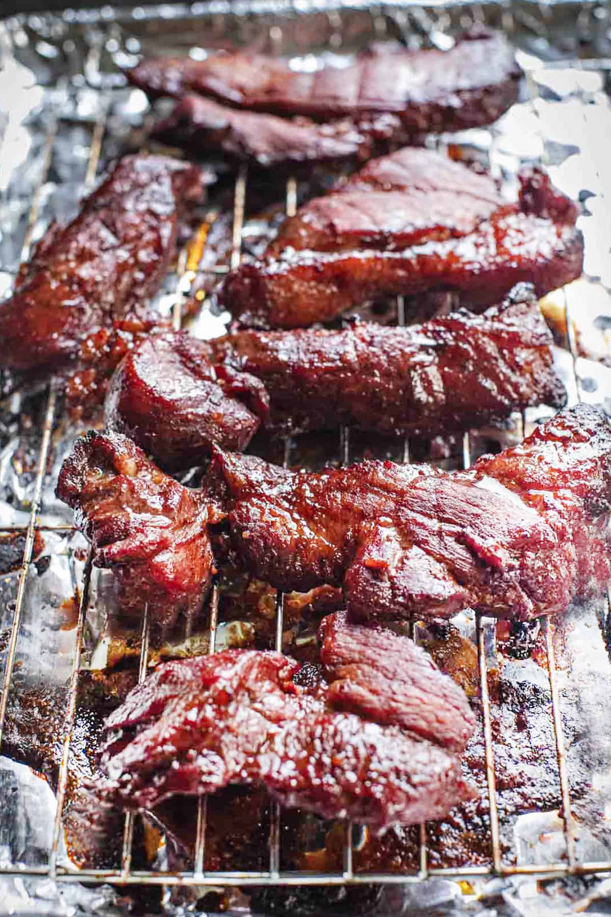 Oven baked pork (char Siu BBQ pork) pieces on an oven rack.