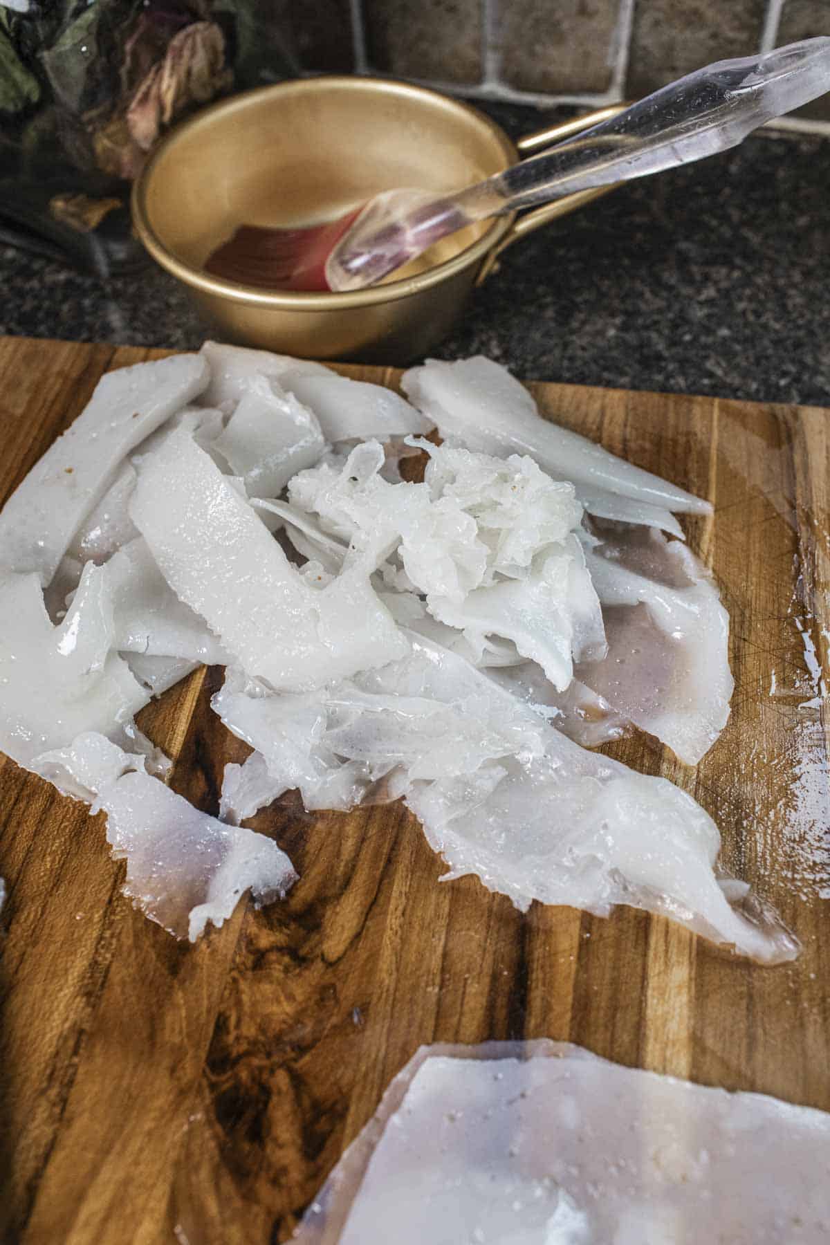 Ripped rice noodles on a cutting board. 