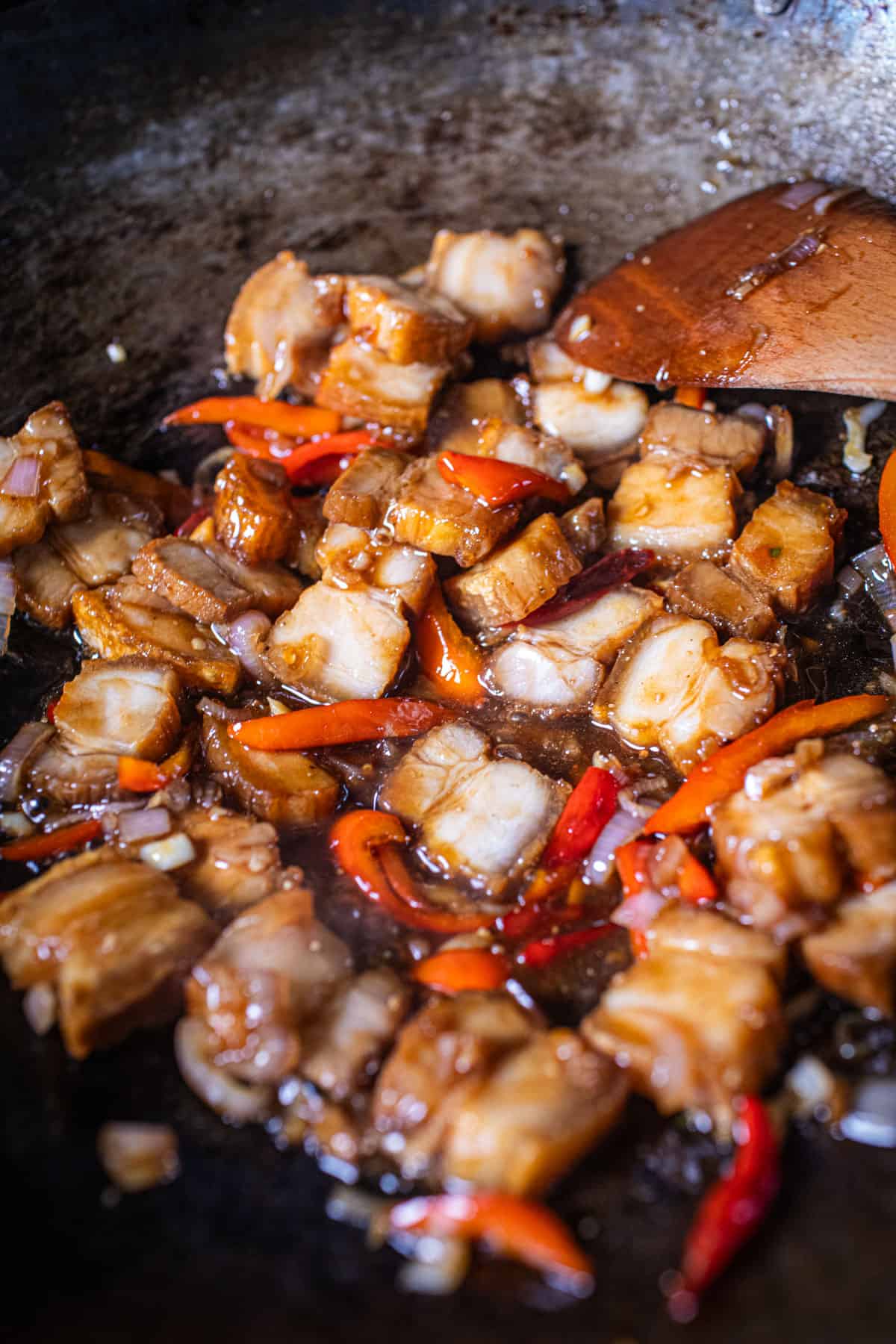 Pork belly moo krop stir fry in a wok with sauce. 