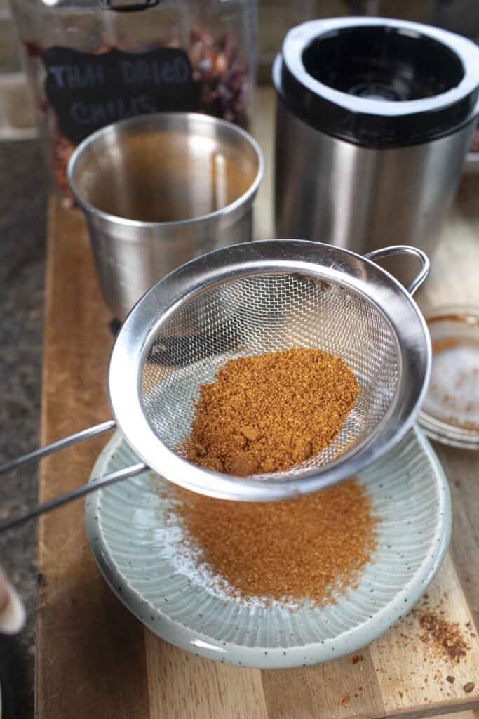 Thai pepper powder in a fine mesh strainer. .