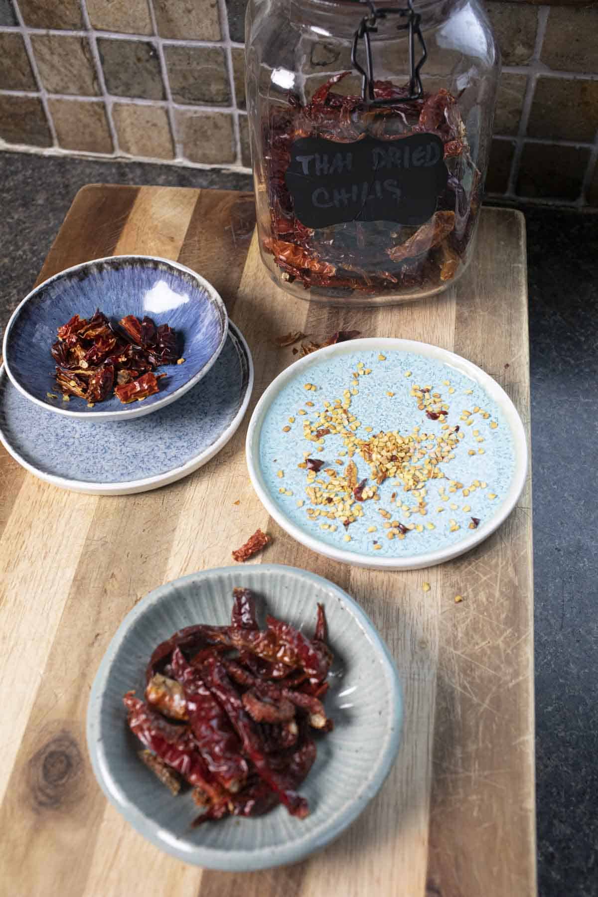 Thai peppers  on small plates on a cutting board.