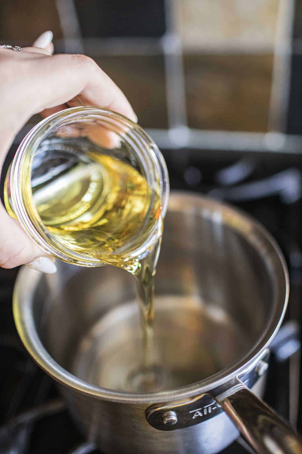 Oil pouring into a saucepan for making chili oil.