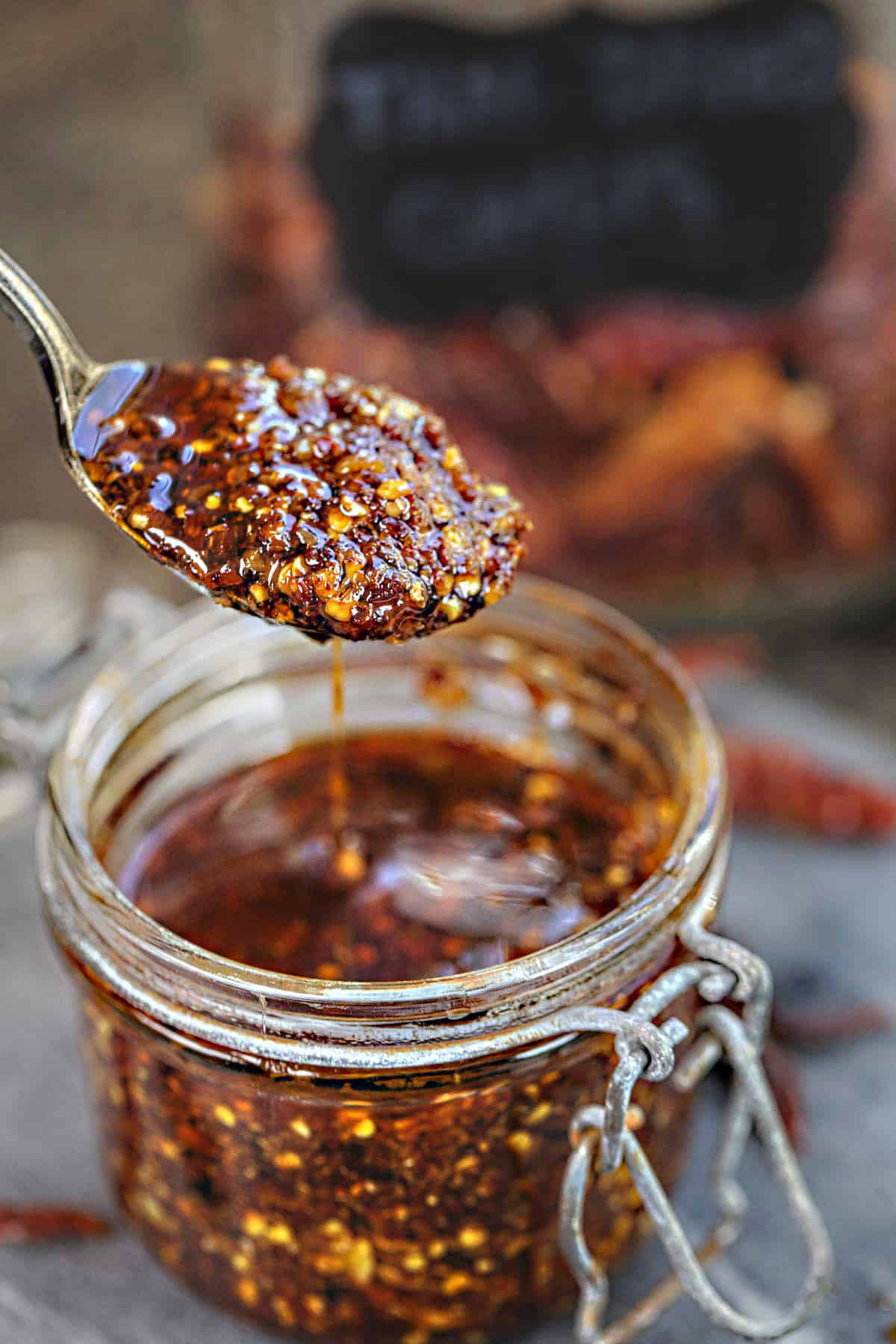 Spoon lifting Thai chili oil from a glass jar.