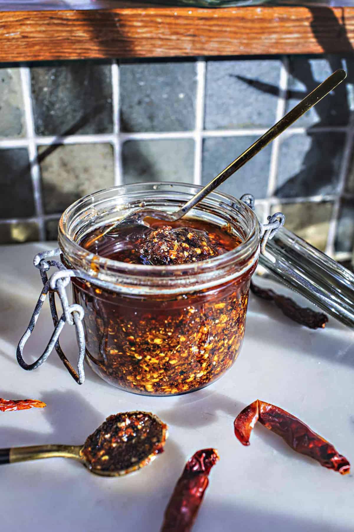 chili oil in a glass jar with chili pepper on the table. 