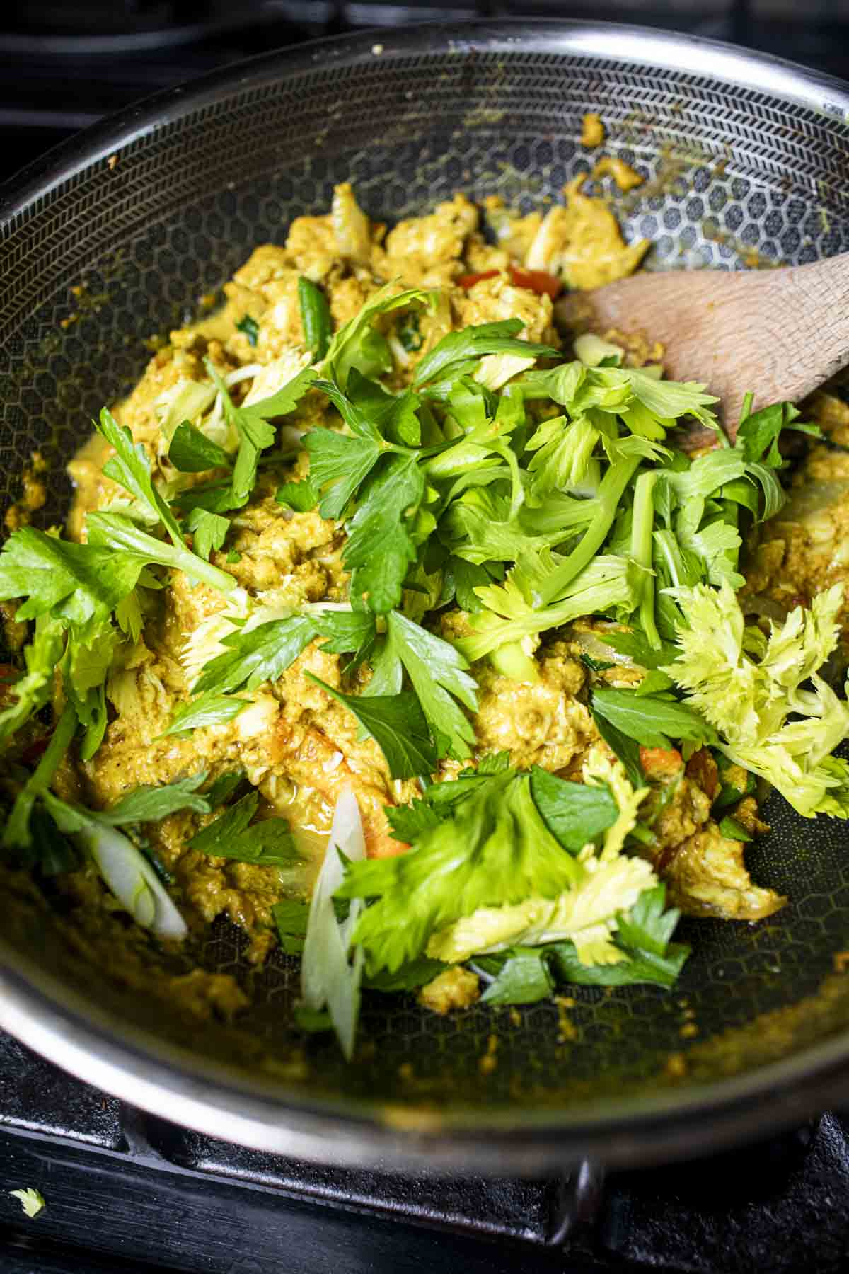 Thai crab curry in a wok with celery leaves on top. 
