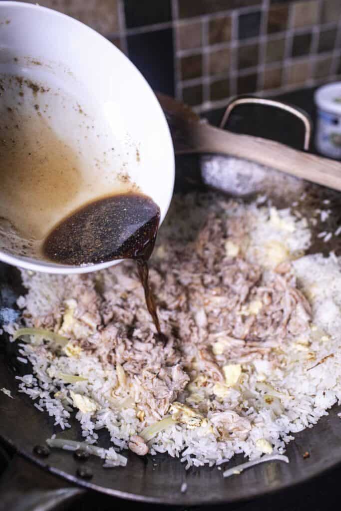 Sauce pouring over crab fried rice in a wok. 