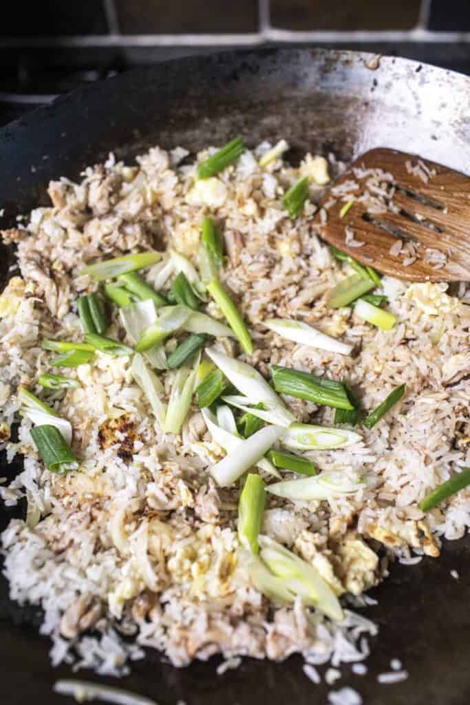 green onion in a wok over fried rice. 