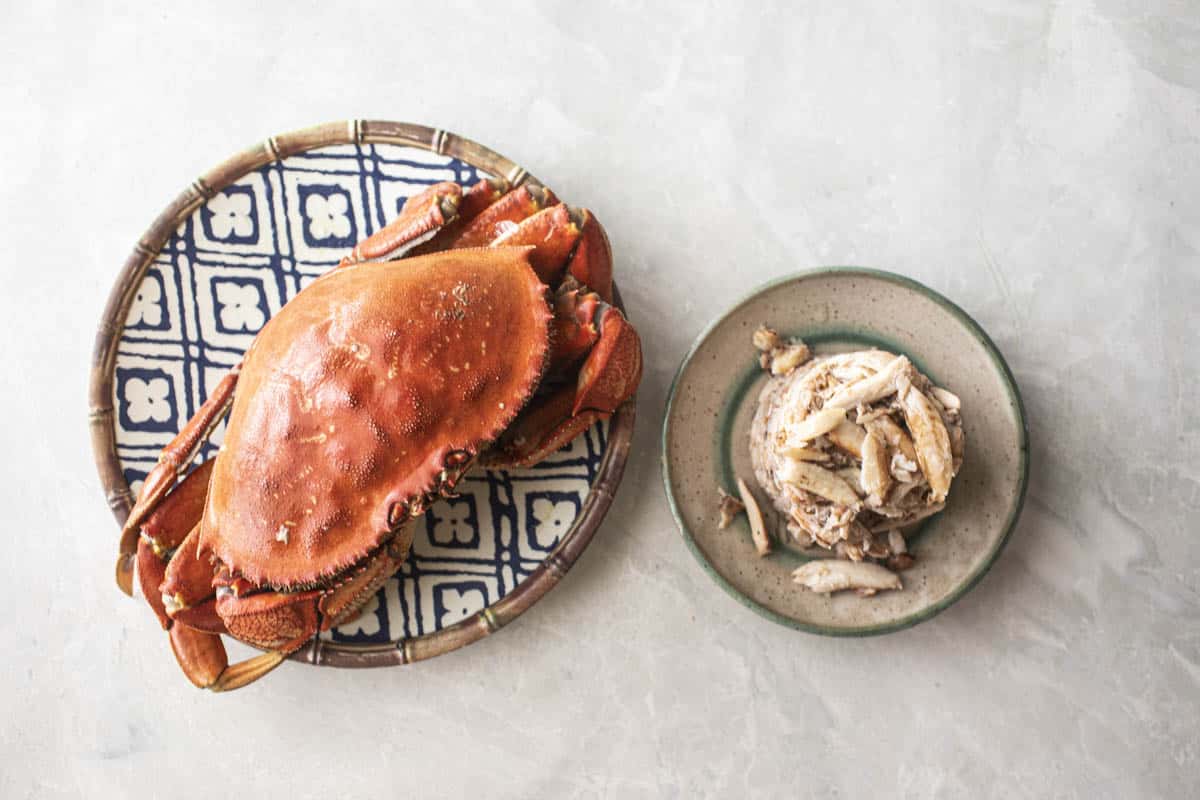 whole crab and shelled crab meat on plates. 