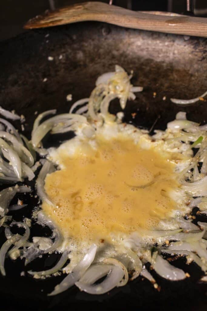 scrambled eggs and onion in a wok. 