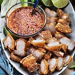 Thai Crispy Pork belly slices on a platter with hot sauce.