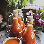 Thai hot sauce, homemade sriracha, in bottles and a small bowl next to bottles.