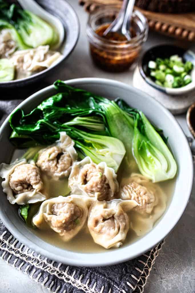 Pork wonton soup in a bowl with bok choy.