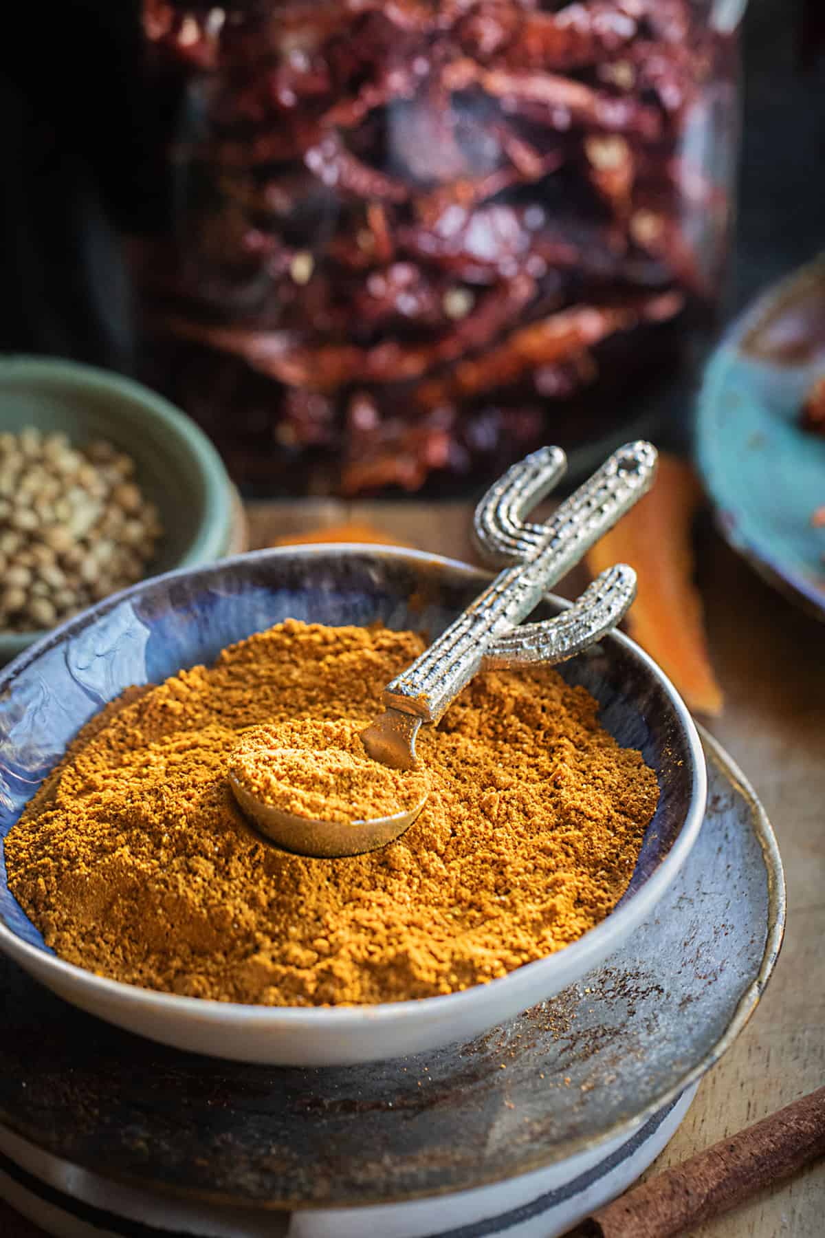 A spoon on top of yellow curry powder in a bowl. 