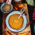 yellow curry powder in a small bowl with spices around it.