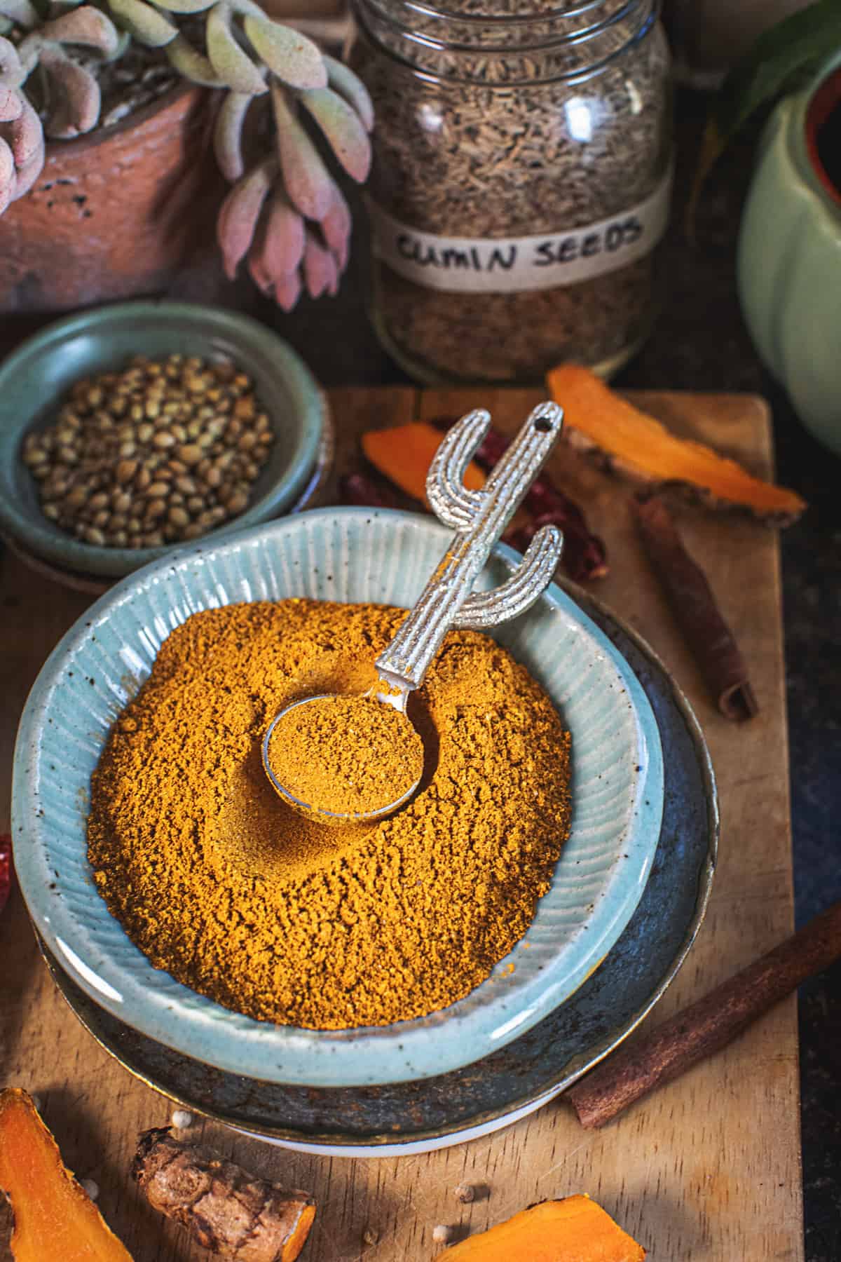 Spoon scooping yellow curry powder in a small platter.