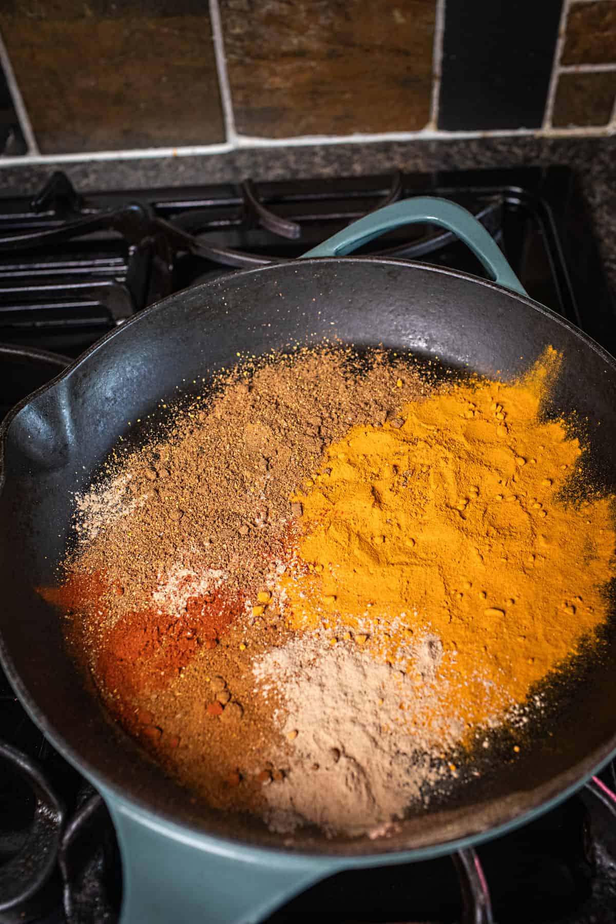 Yellow curry powder mix in a pan on the stovetop.