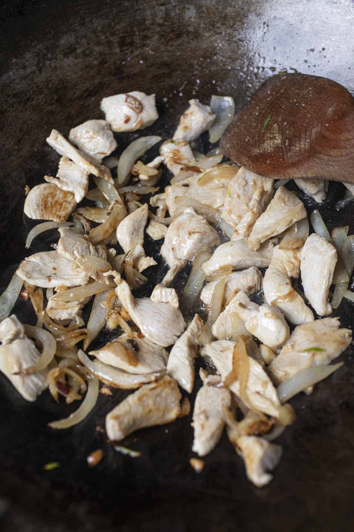 chicken and onion for yellow fried rice recipe in a wok. 