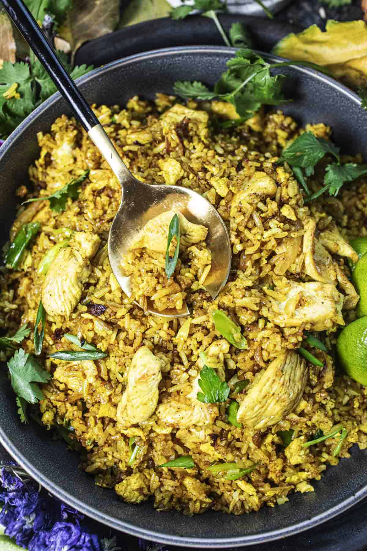 Thai yellow fried rice in a bowl with lime wedges on the side. 