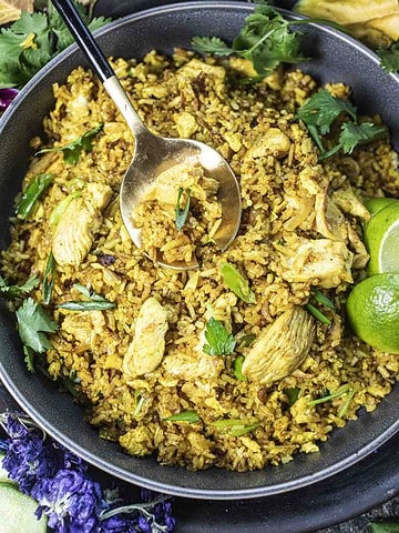 Thai yellow fried rice in a bowl with a spoon in the middle.