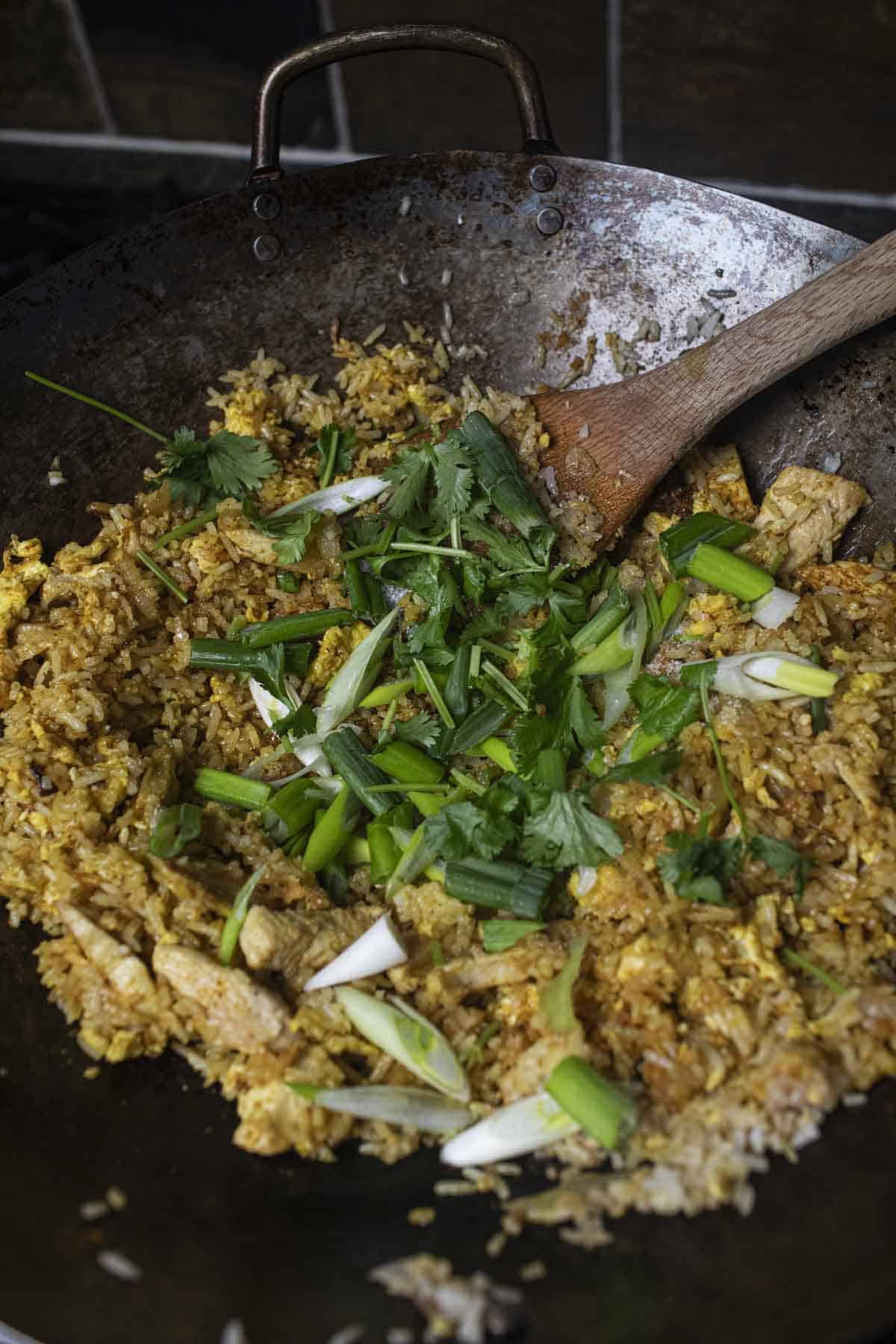 Fried yellow rice with cilantro and green onions in a wok. 