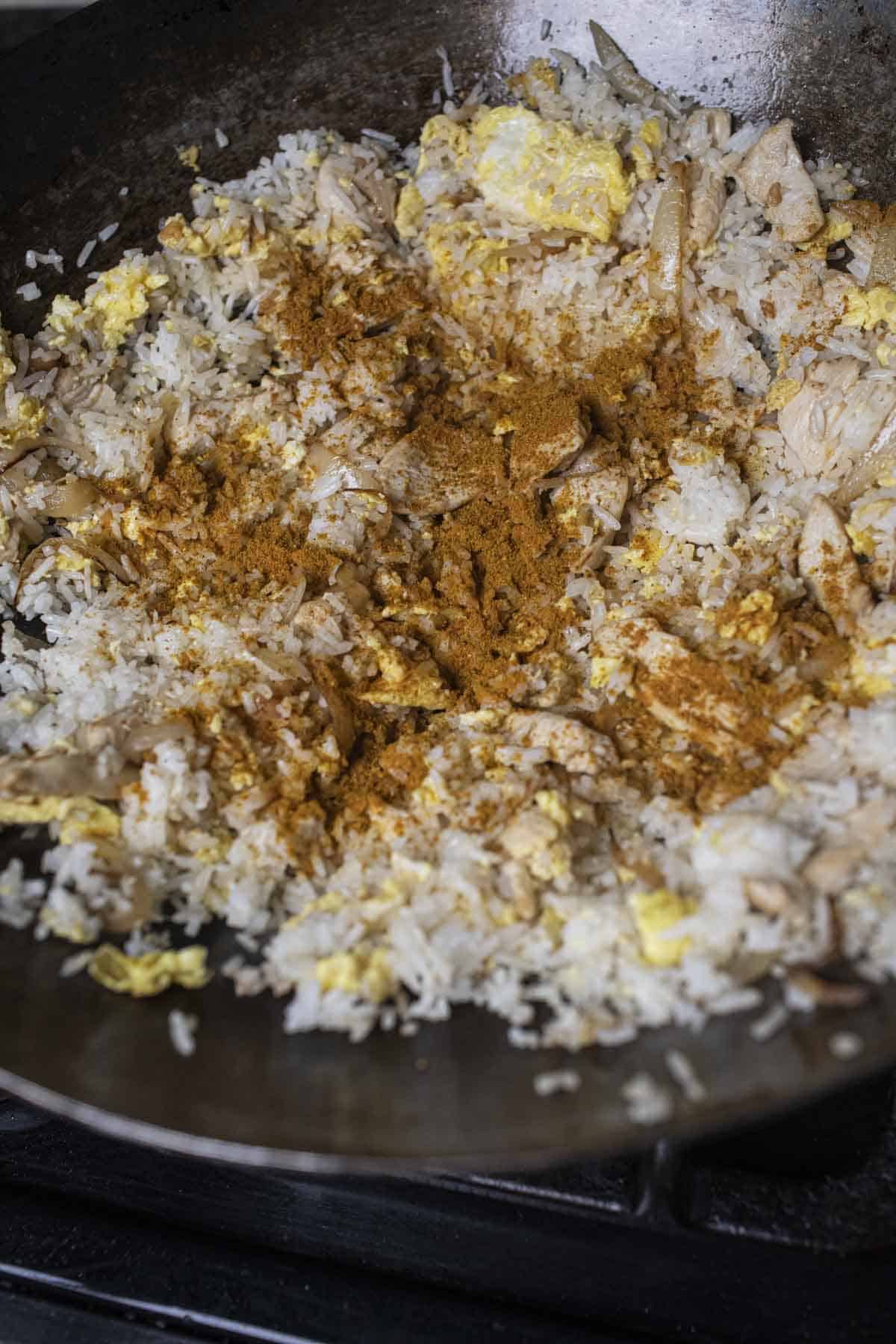 Fried rice with yellow curry powder in a wok. 