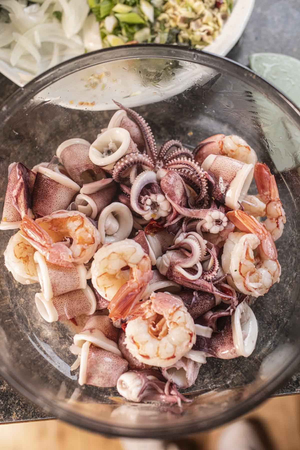 Cooked shrimp and squid in a glass bowl on the counter. 