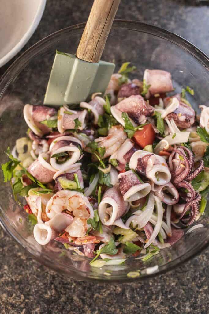 Yum Talay Thai salad mix in a bowl with spatula. 