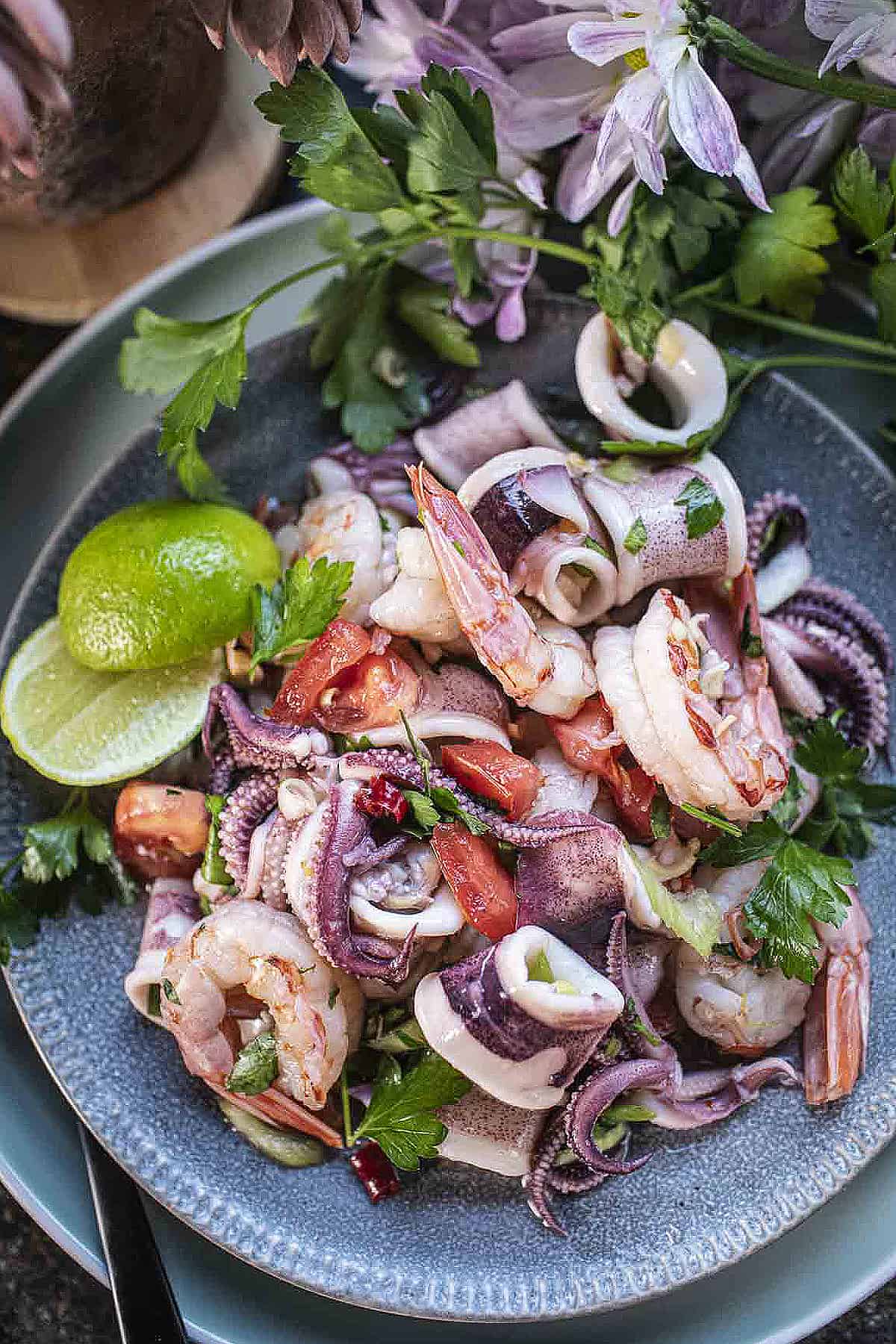 Thai seafood salad on a platter with lime wedges on the side. 