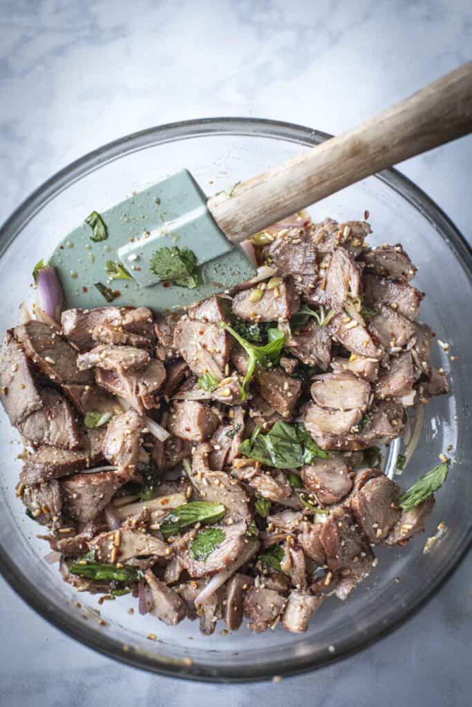 pork waterfall salad in a bowl with spatula. 