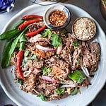 Thai Moo Nam Tok salad on a plate with chilie and rice.