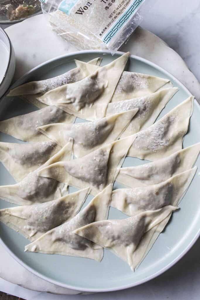 Triangle shaped wontons on a plate.