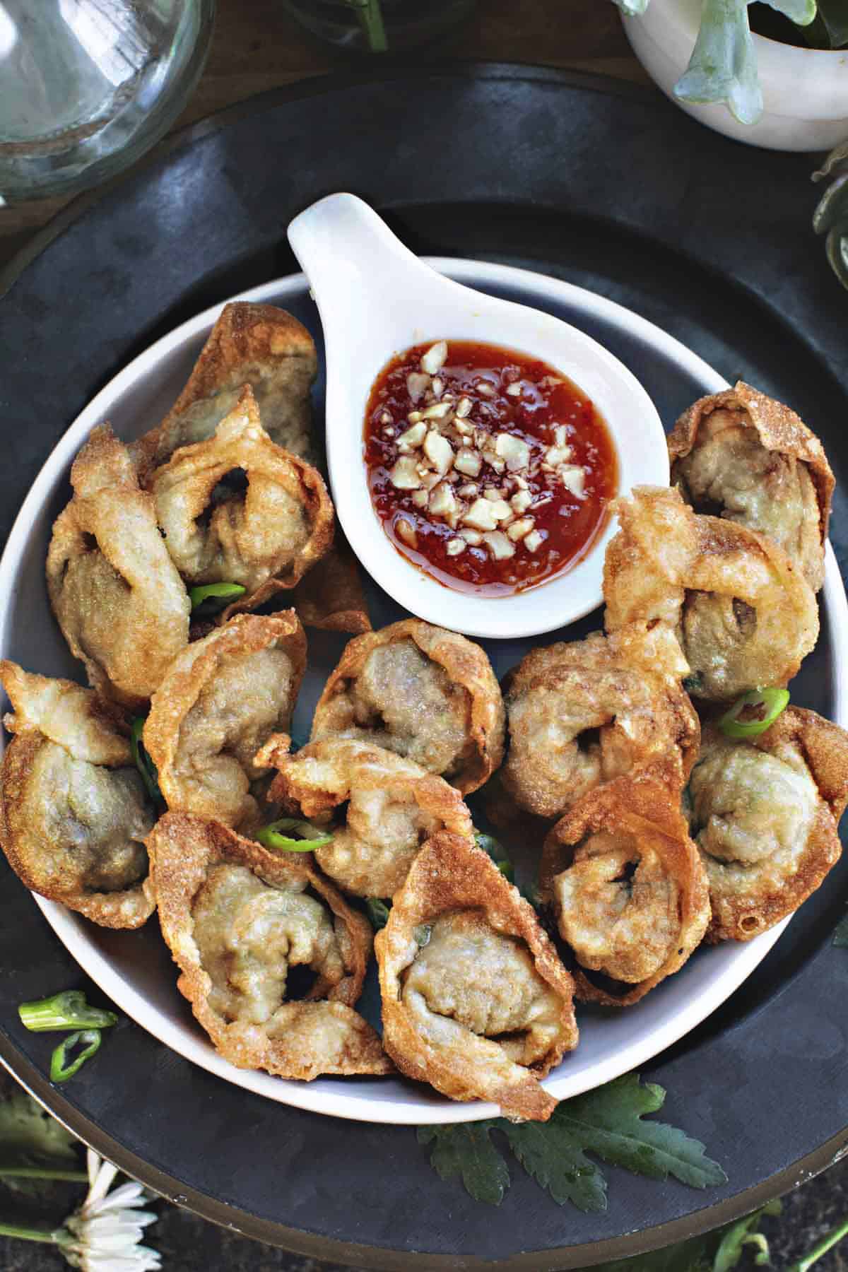 crispy fried wontons on a plate with chili dipping sauce