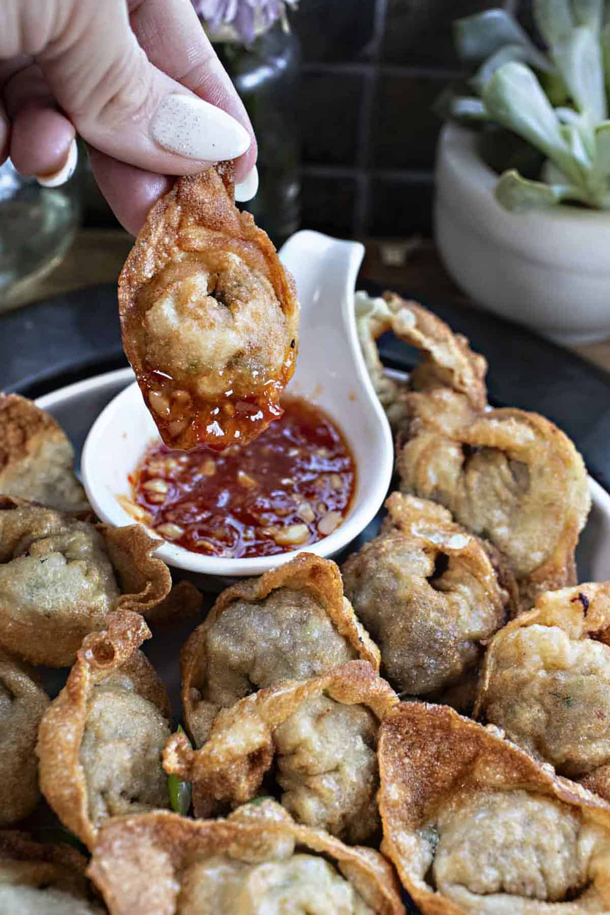 Fried beef wontons on a plate with a dipping sauce. 