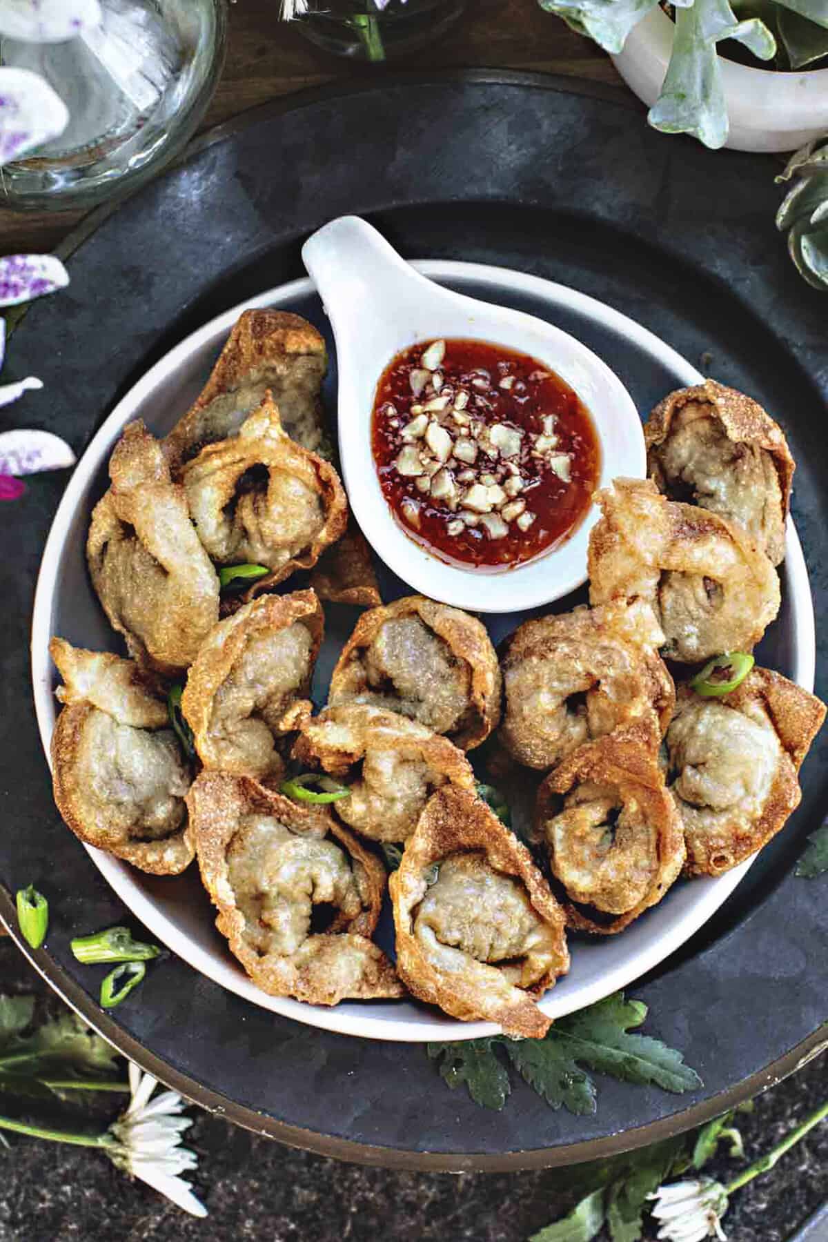 Beef wontons on a plate with chili dipping sauce. 