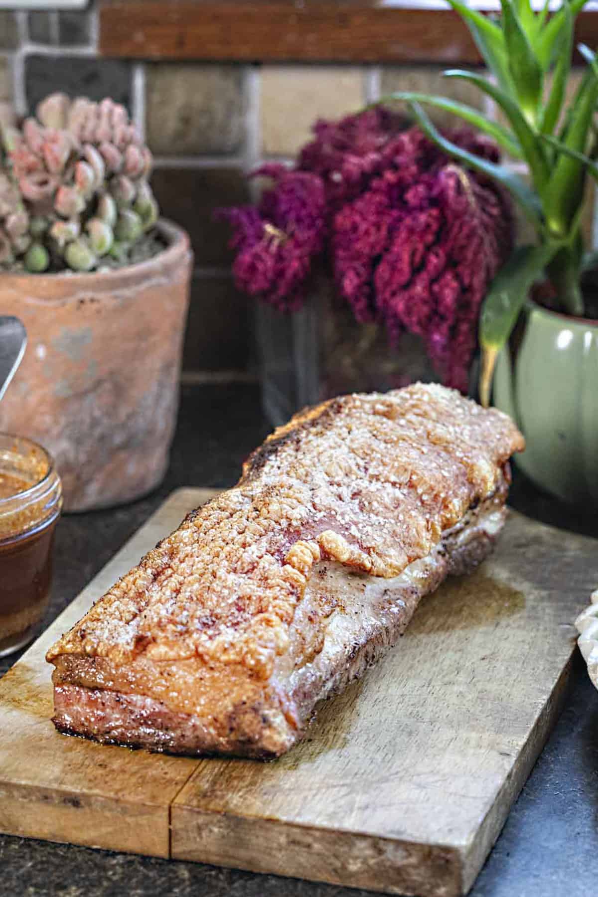 Large piece of cooked pork belly on a cutting board. 