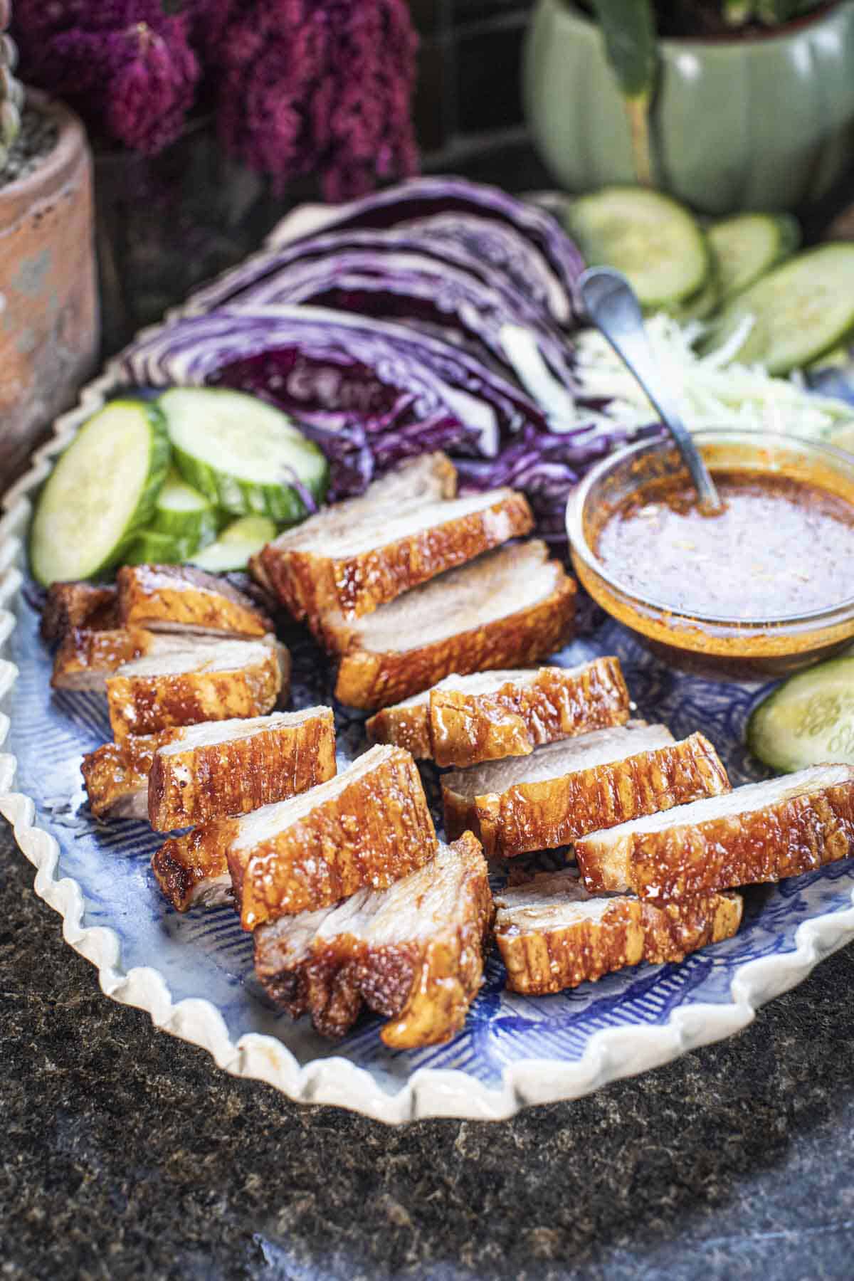 Five spice pork belly slices on a platter with sauce