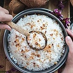 A spoon lifting Coconut Jasmine Rice from a bowl.