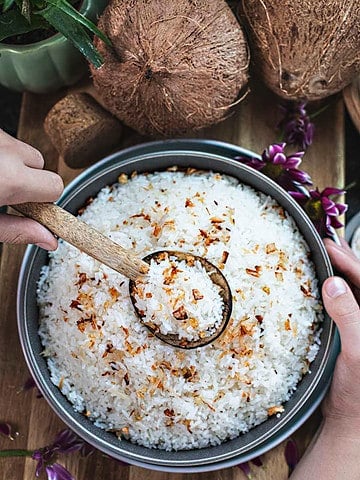 A spoon lifting Coconut Jasmine Rice from a bowl.