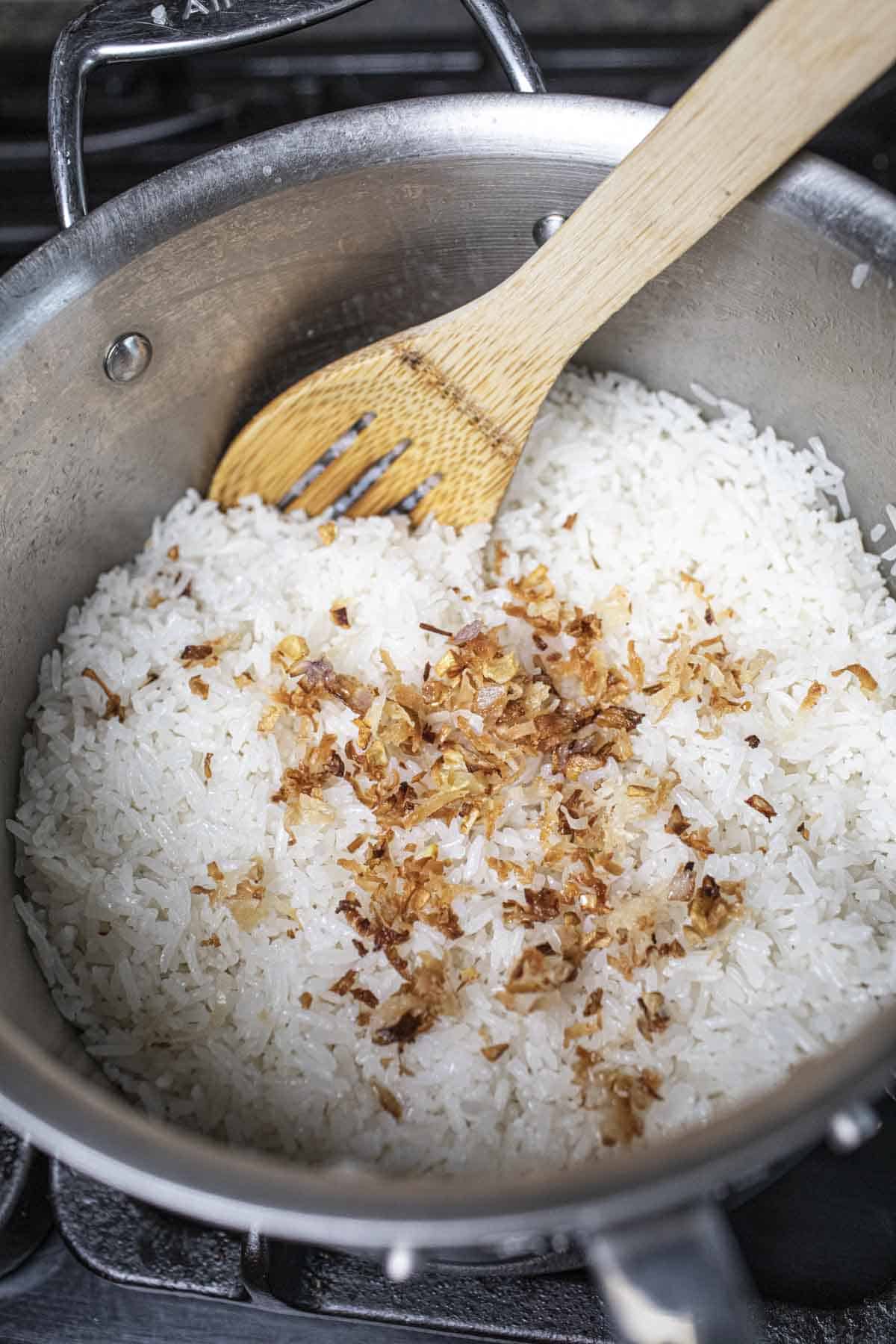 A wooden spatula in pot of coconut rice.