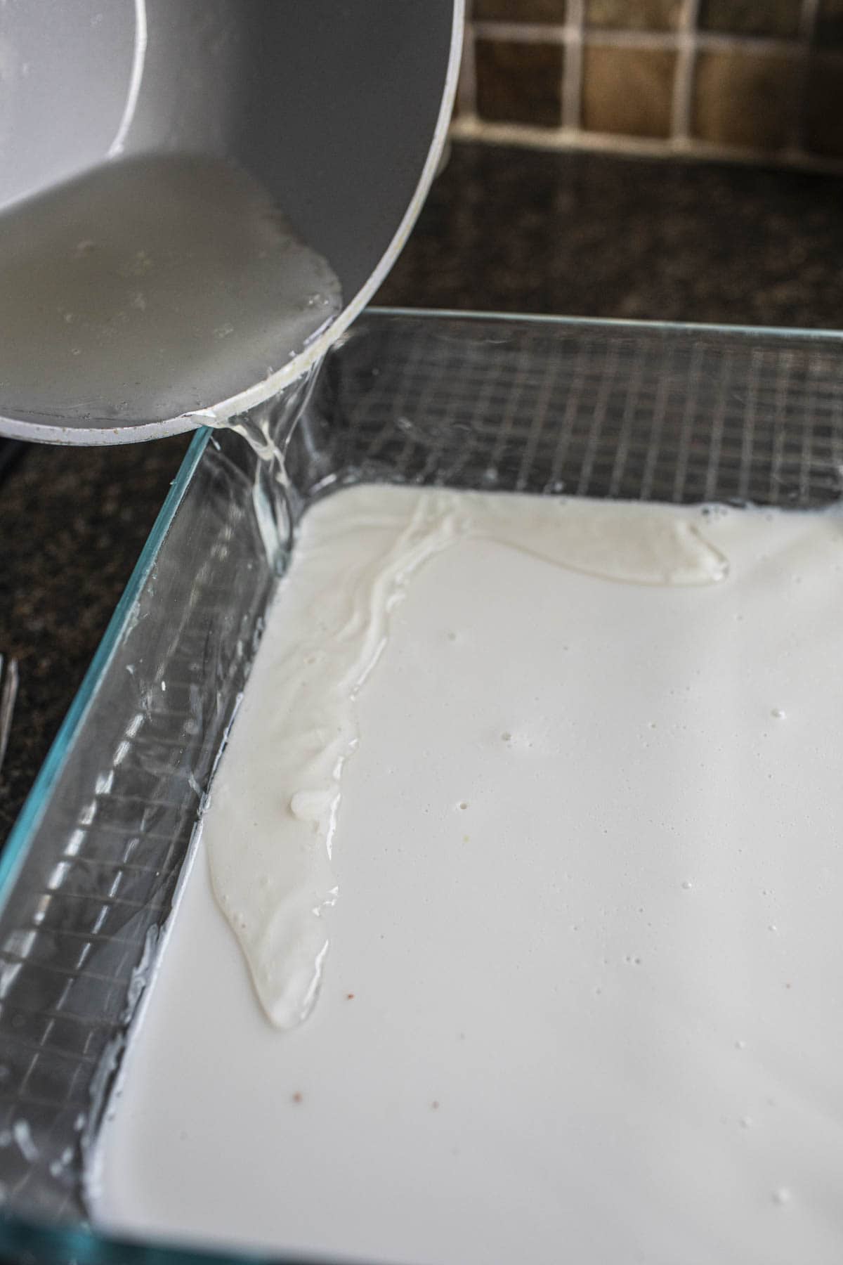 Hot water pouring into a pan with coconut jelly.