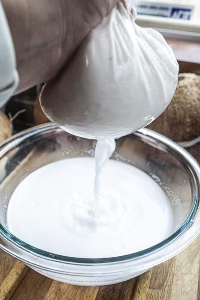 Coconut water in a muslin cloth with milk dripping into a jar. 